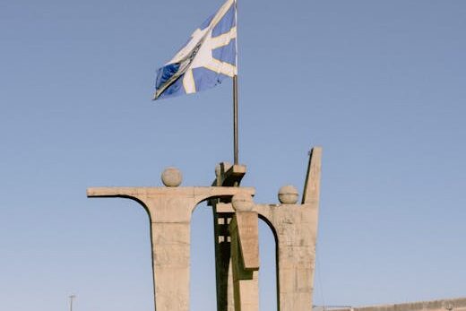 Concrete monument in Anápolis, Brazil under a clear blue sky displaying a flag.